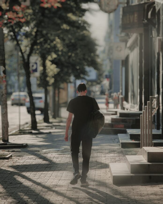 Photo by Kyrylo Kholopkin man in black hoodie walking on sidewalk during daytime
