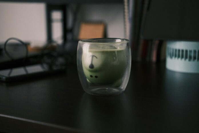 a glass filled with liquid sitting on top of a desk