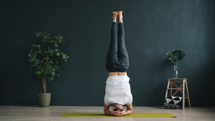 Woman performing a headstand yoga pose indoors.