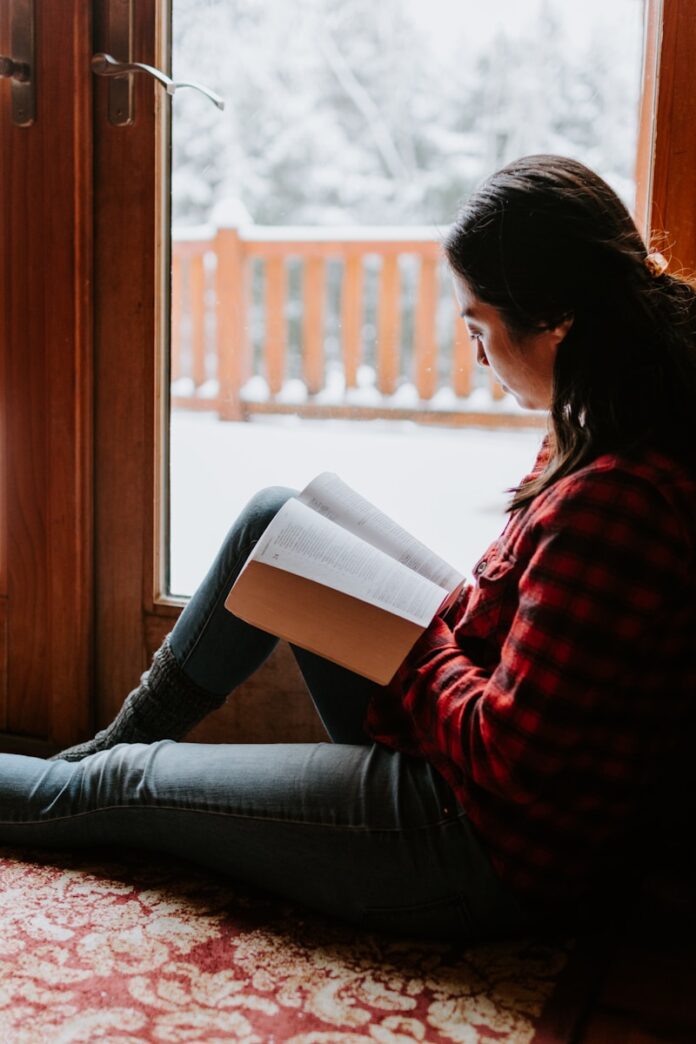 Photo by Kelly Sikkema woman in red and black striped long sleeve shirt and blue denim jeans sitting on brown