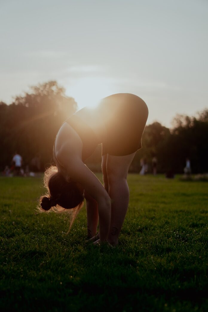 Photo by Chuko Cribb woman in white bikini bottom kneeling on green grass field during sunset