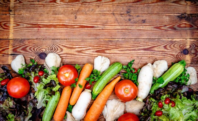 Photo by AZIZ KOURI Fresh colorful vegetables arranged on a rustic wooden background.